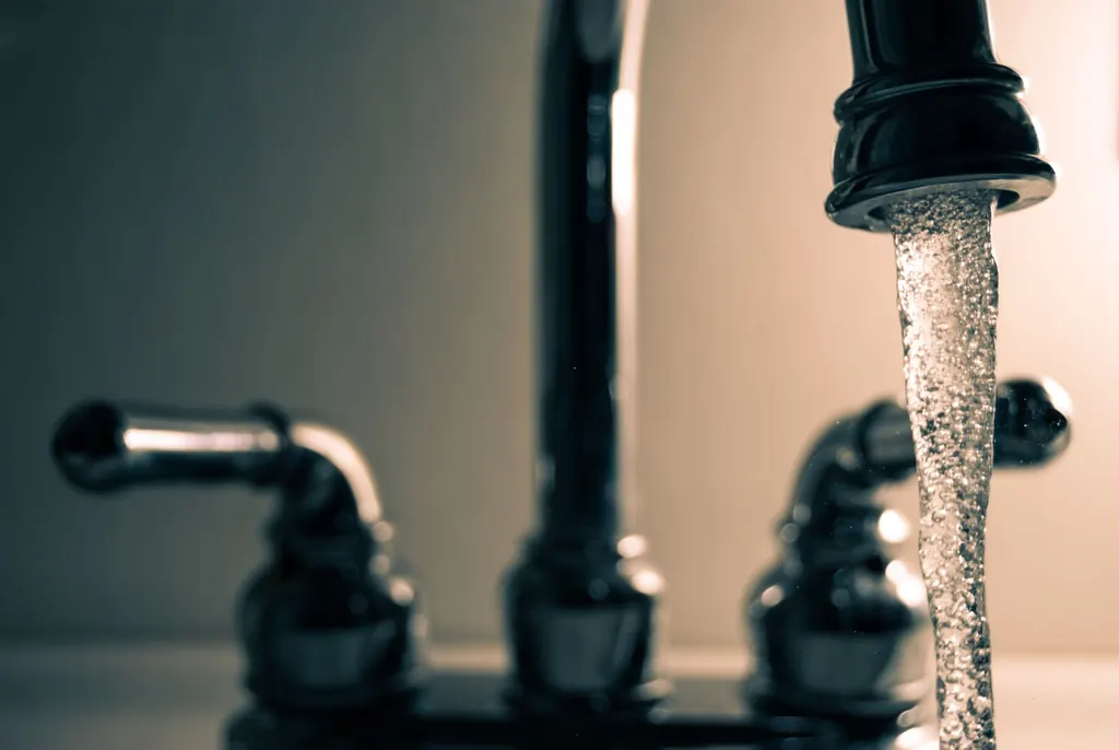 Clear water flowing from a steel faucet — recommended for Las Vegas hard water treatment